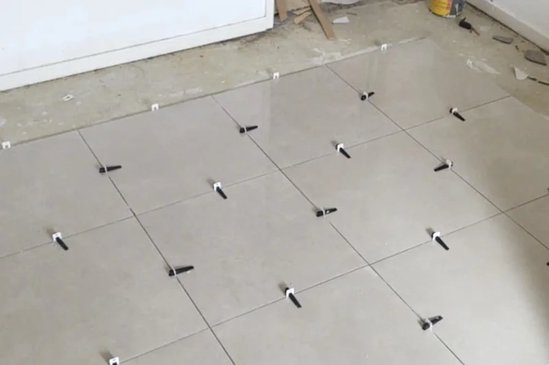 Floor tiles being laid with levelling clips across a room — Mitchell Hunter Handyman, Whitstable | mitchhandyman.co.uk